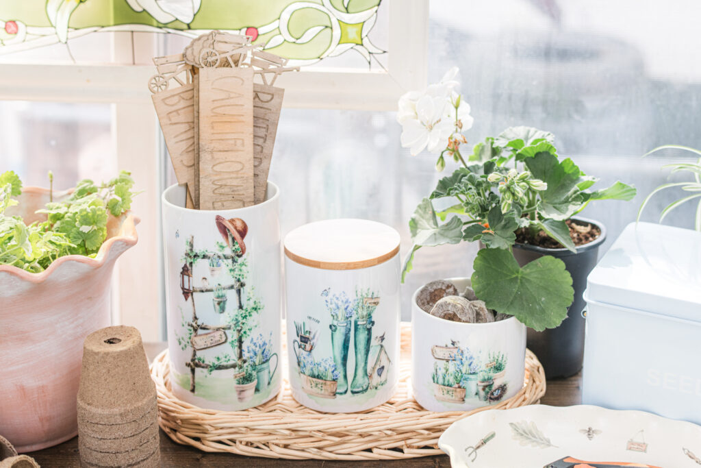 Pretty country garden, canisters, sitting in a wicker tray on a potting table. 