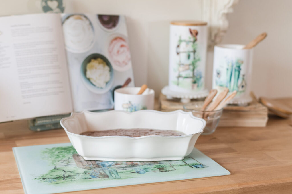 Hot casserole dish from the oven placed on a glass cutting board to protect butcher block from heat.