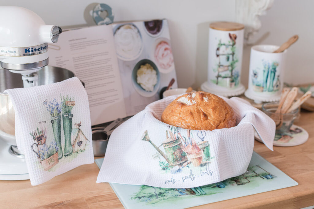 Garden themed tea towel lining a bread basket with sourdough 
