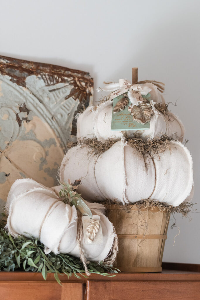 DIY drop cloth topiary pumpkins styled on top of a Hoosier cabinet with a tin rusted antique tile behind it for fall 