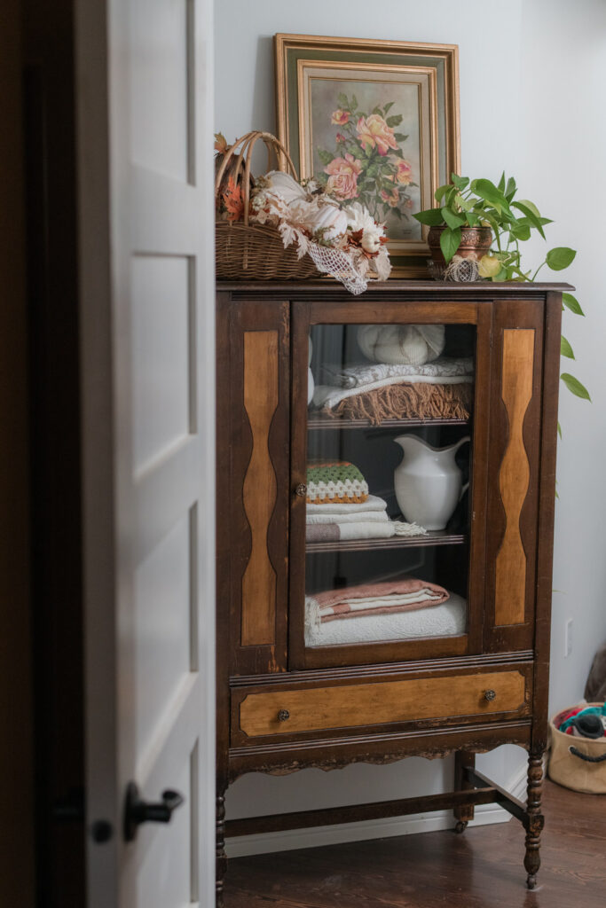 Vintage china cabinet turned into a hallway linen closet and decorated for fall 