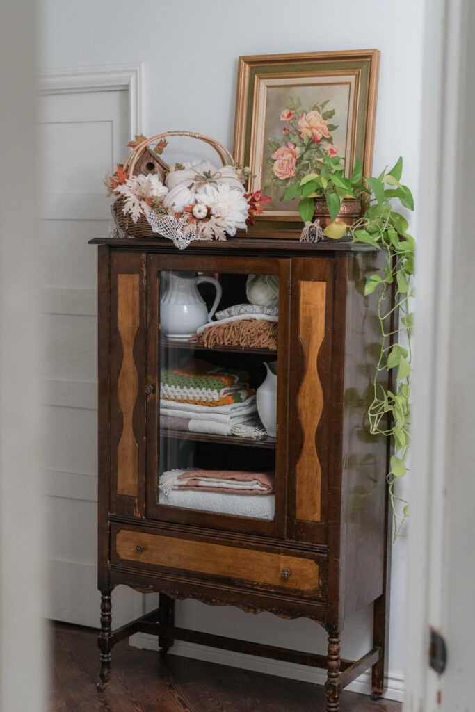 Vintage China cabinet turned into charming linen closet in the hallway and decorated for fall 