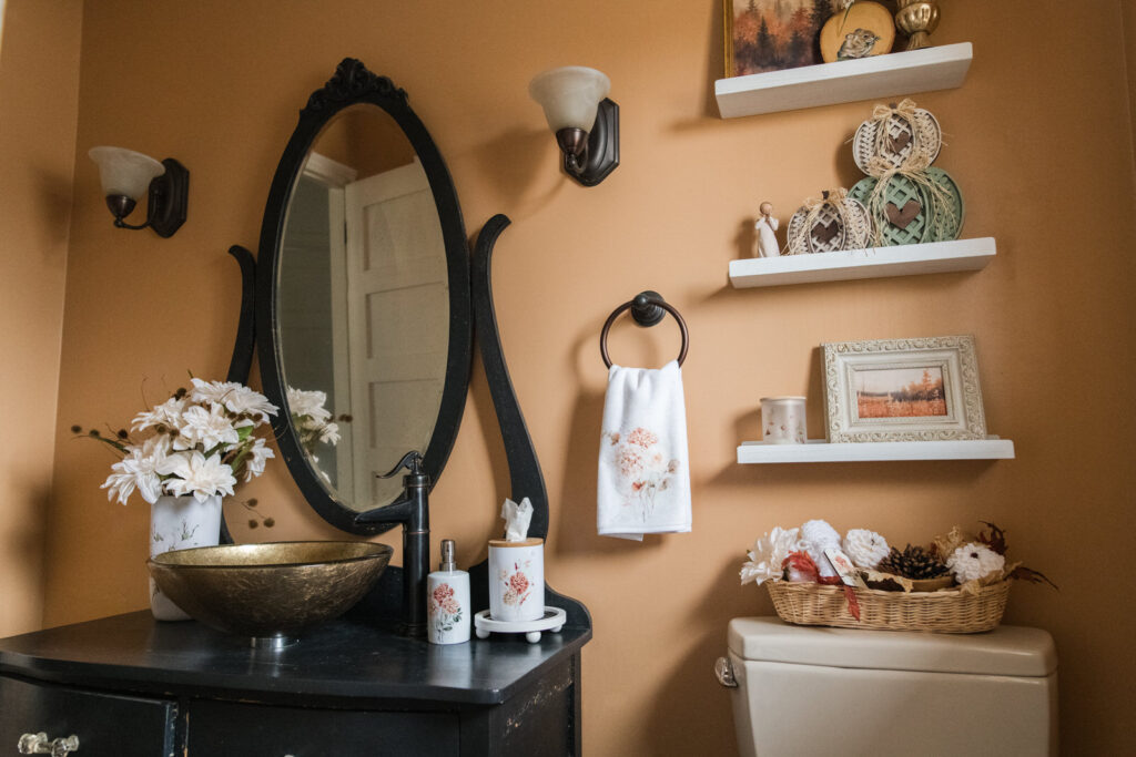 Old dresser turned vanity with a modern sink and nostalgic decor for fall on shelving in the bathroom