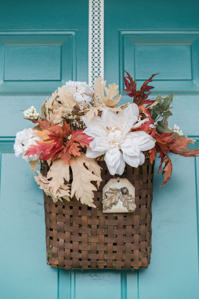 Fall basket, hanging on front door, full of florals and adorned with a handmade tag