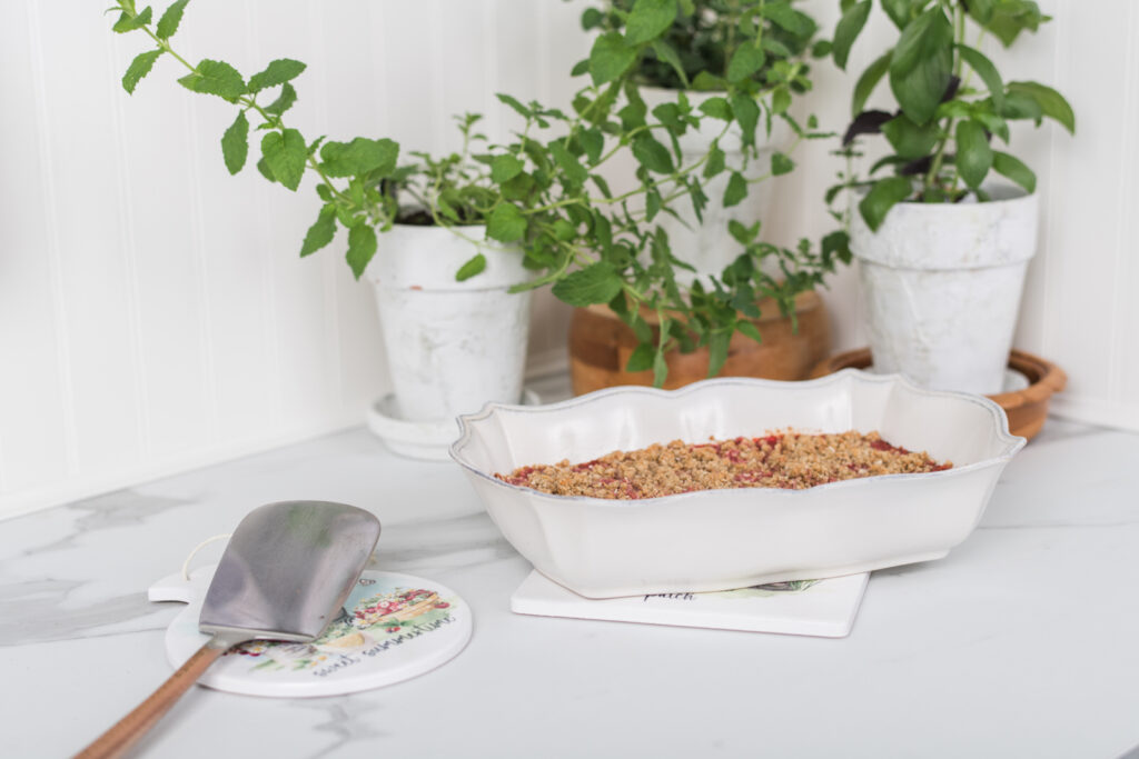 Rectangular ceramic trivet with strawberries and daisies in a cozy kitchen, with a small round trivet being used a spoon rest