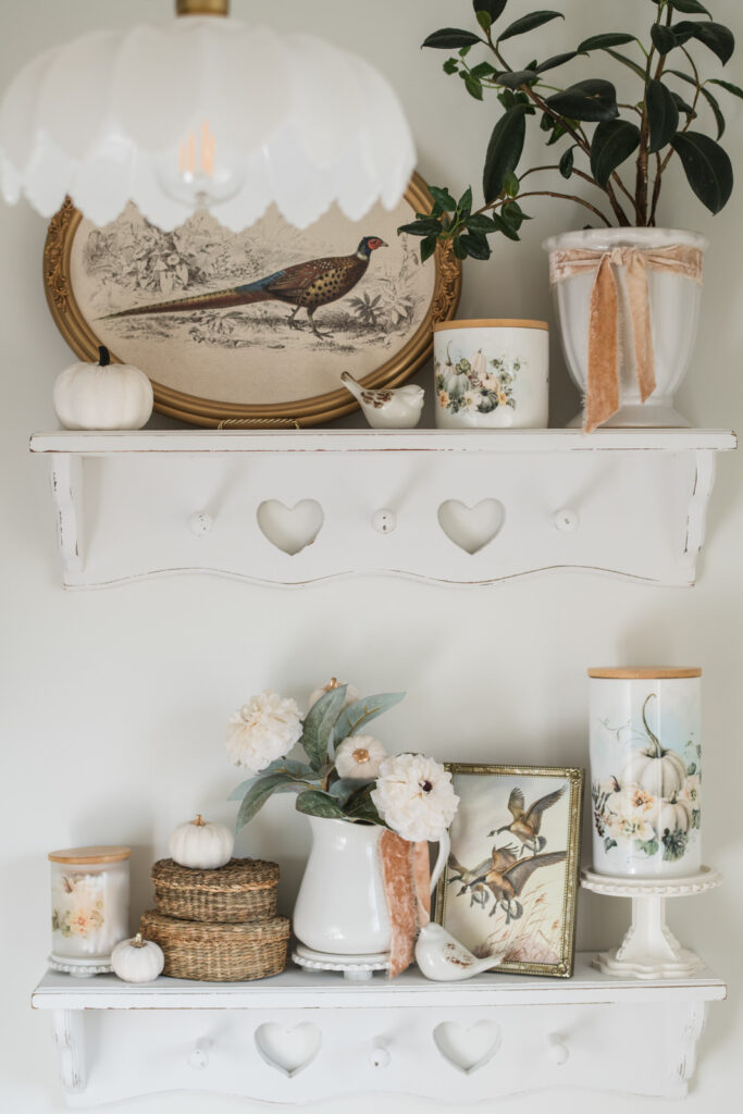 Vintage-inspired bathroom shelves styled with thrifted frames, autumn prints, and cottage-style fall decor.