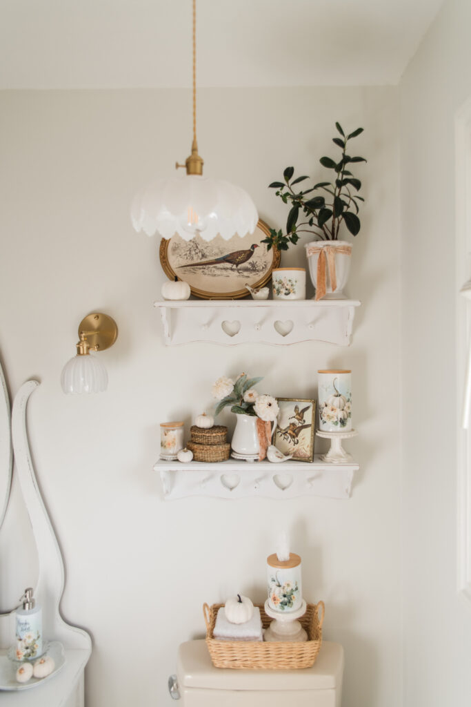 Thrifted bathroom decor styled on shelves with wicker baskets and vintage looking prints