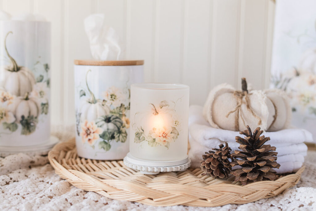 Fall, bathroom, decor, featuring a candle holder, and a ceramic tissue holder on a wicker tray with pinecones, a pumpkin, and face cloths 