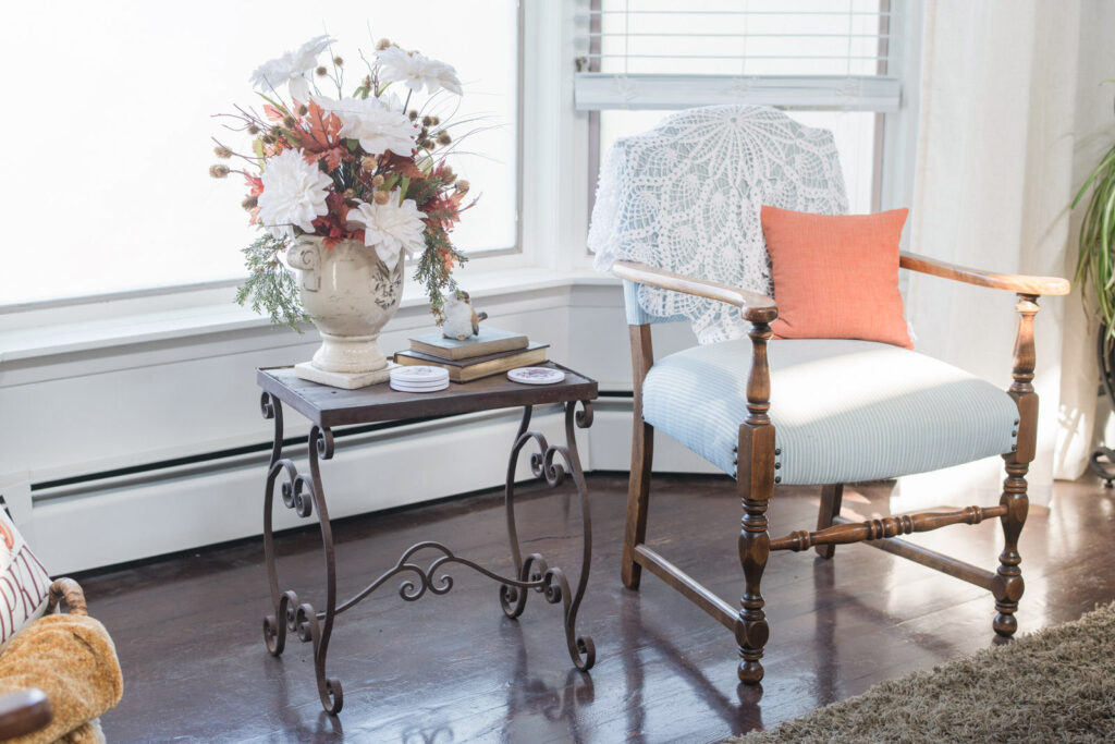 Bay window nook with vintage chair, crocheted lace throw, and rust pillow for fall