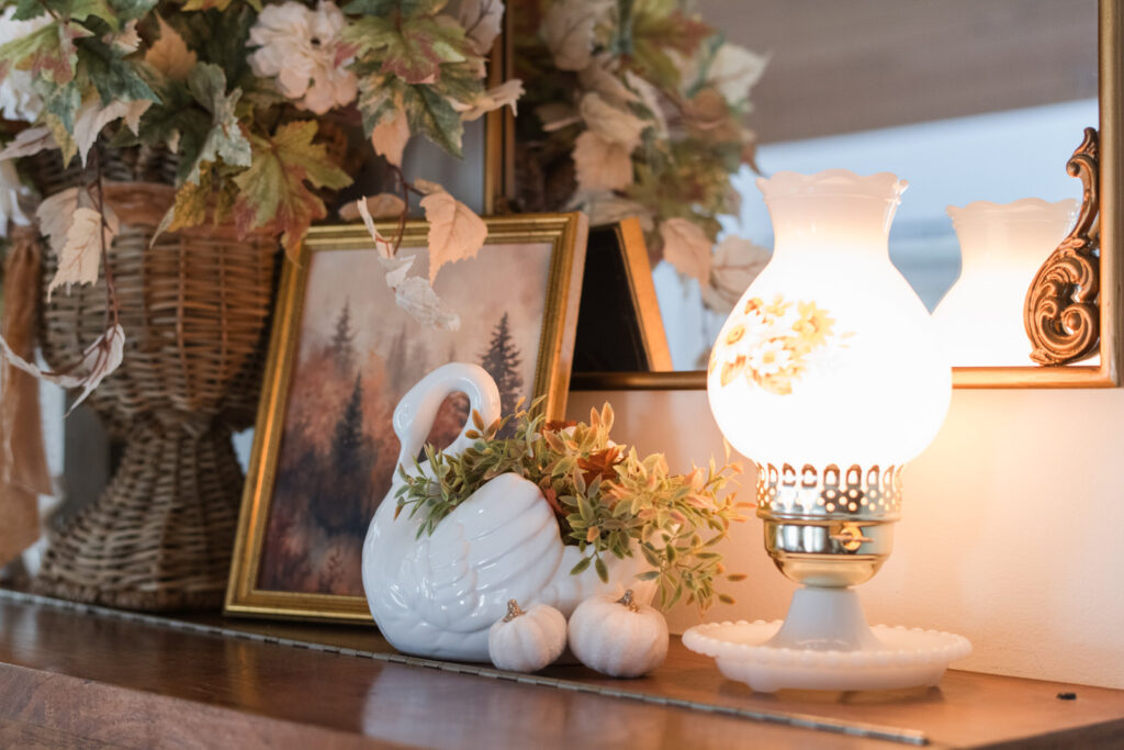 Seasonal piano decor with a vintage milk glass lamp light, and swan planter with fall florals
