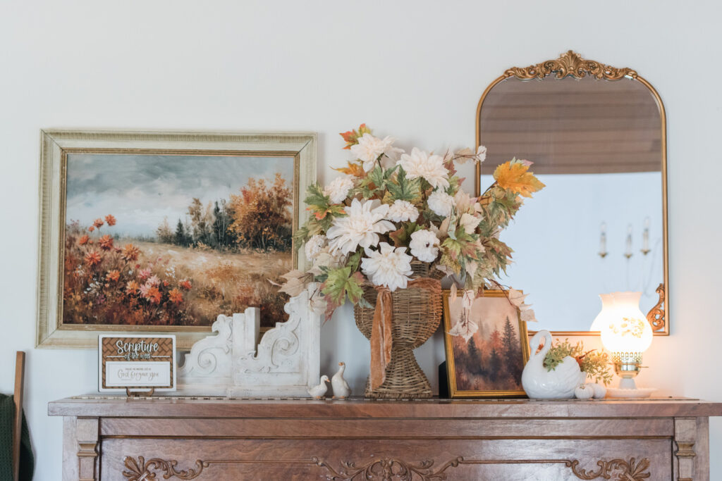 Fall decorating idea with piano top styled with swan planter, geese figurines, and vintage lamp, mirror and art work