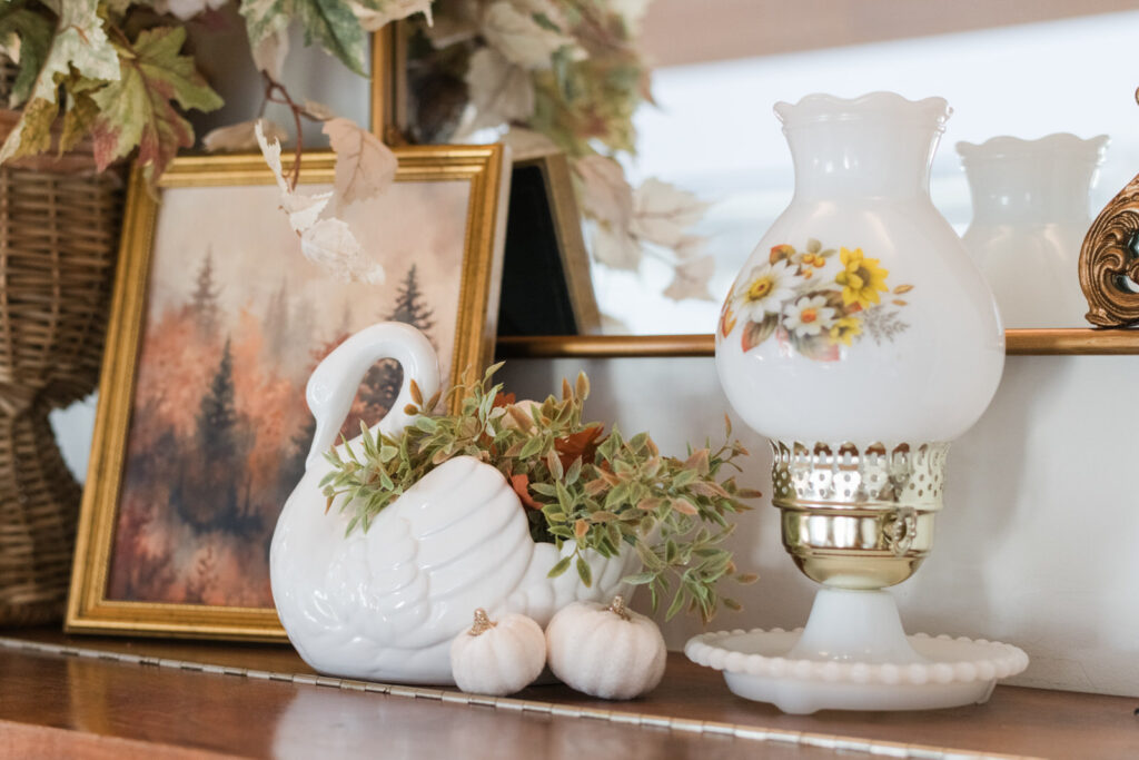 Fall decorating idea with piano top styled with swan planter, geese figurines, and vintage lamp