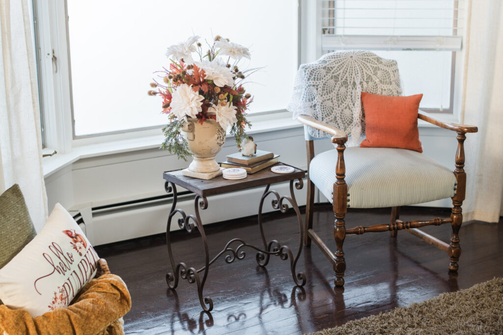 Fall reading nook idea with vintage chair and basket of blankets in bay window