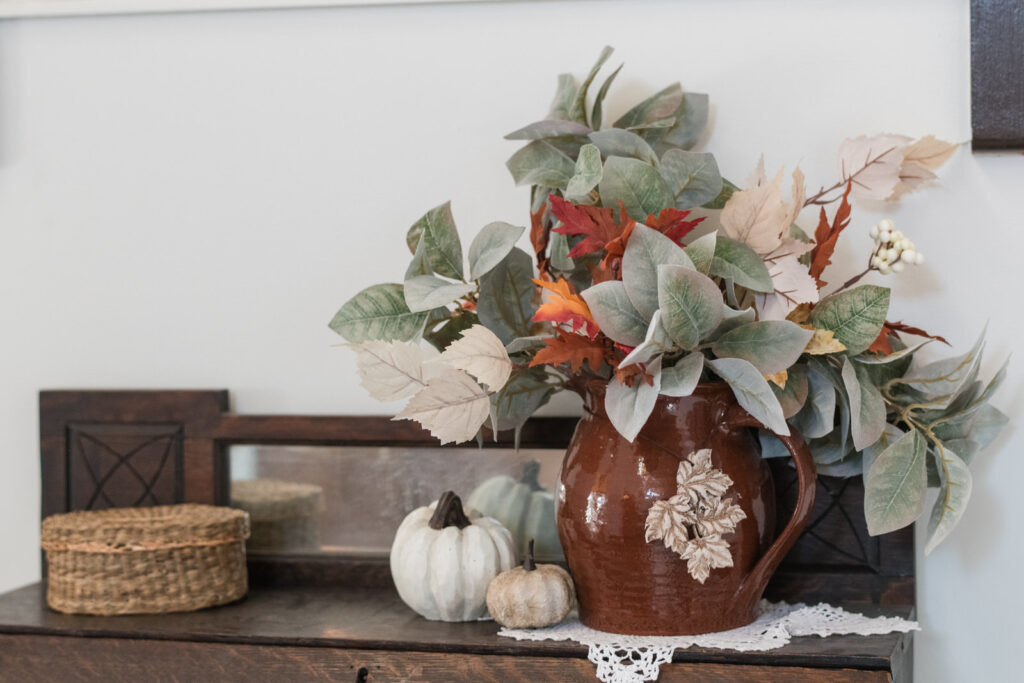 Antique wooden desk styled for fall with crock of florals and leaf charm
