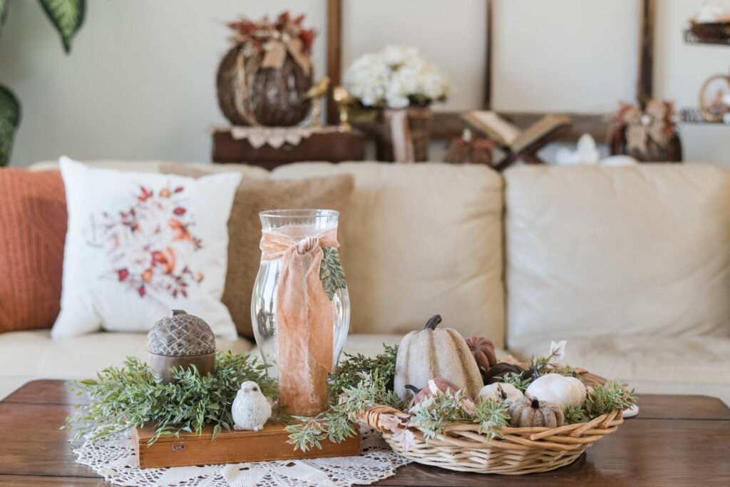 Wooden coffee table decorated for fall with greenery, gourds, and a candle