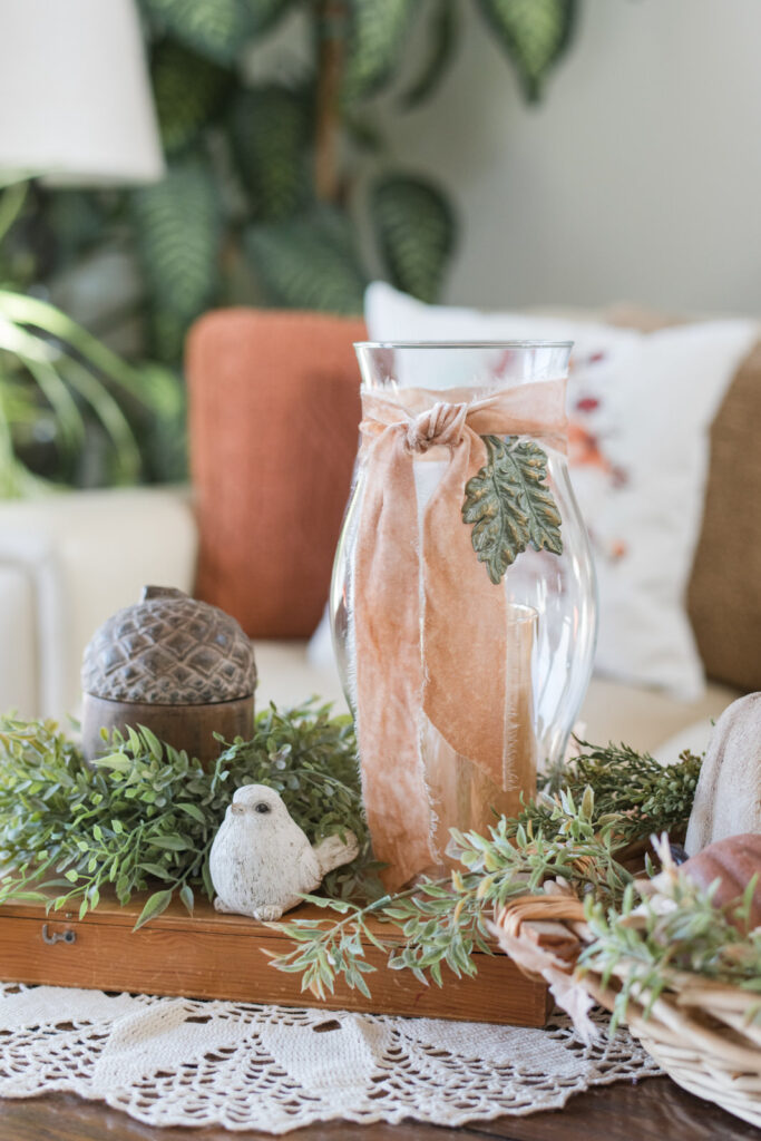 Vintage doily layered under fall basket with pumpkins and pinecones on wooden table