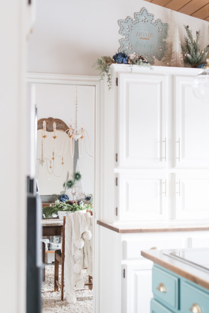 a peak into a christmas dining room from the kitchen