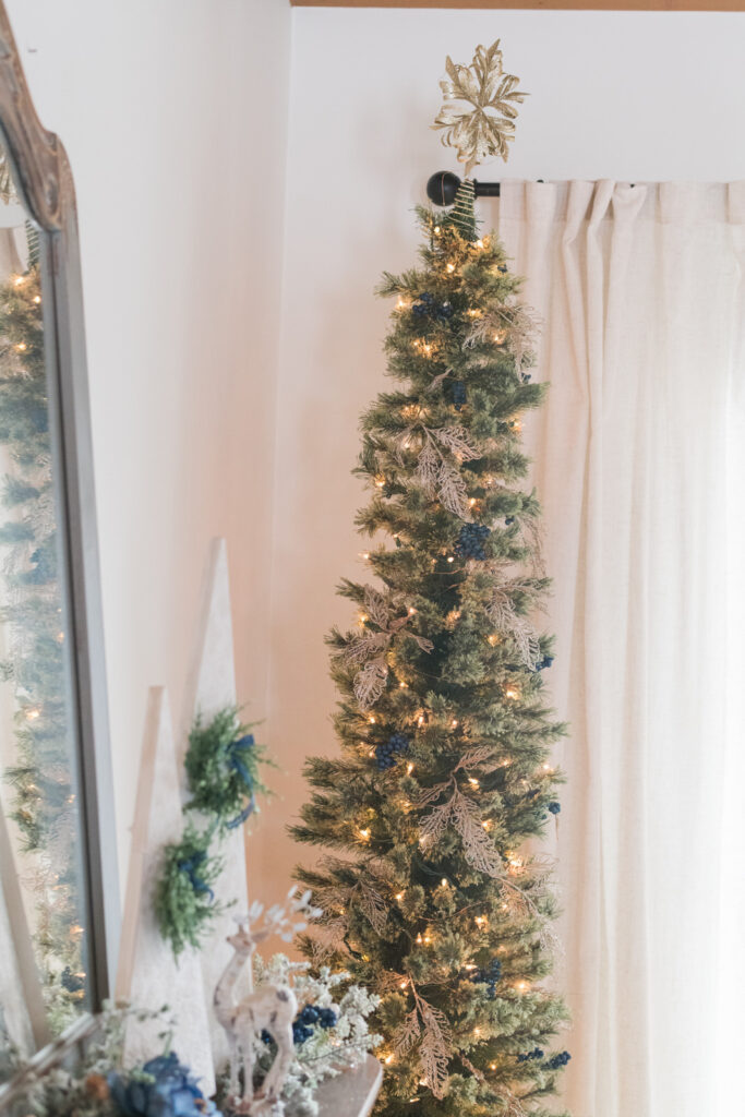 Pencil Christmas tree with gold leaves and navy berries in dining room corner