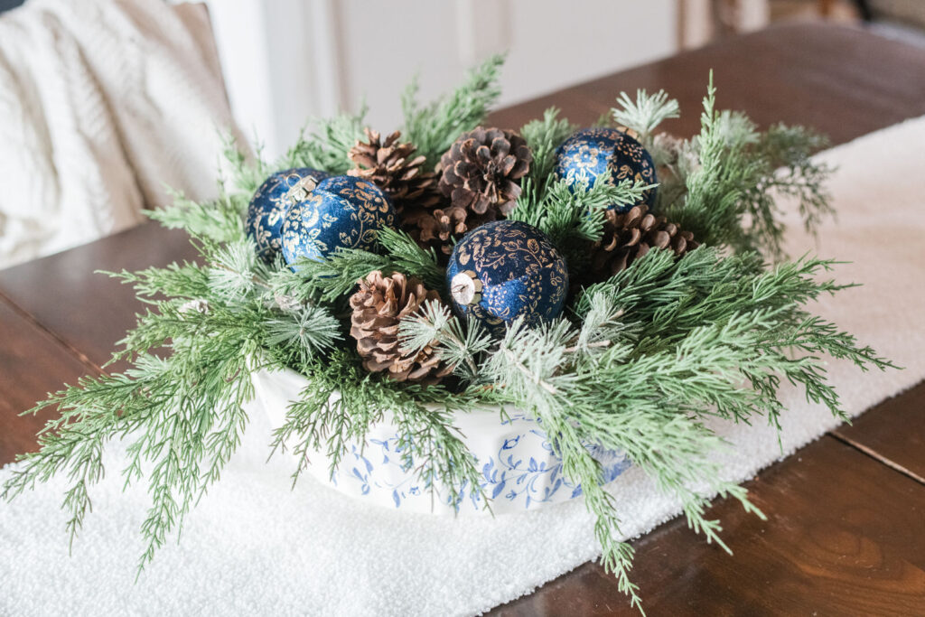 Blue and white bowl centerpiece with pinecones and greenery
