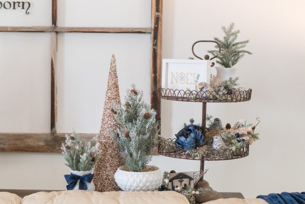 Tiered tray styled for Christmas with trees, ornaments, and nativity