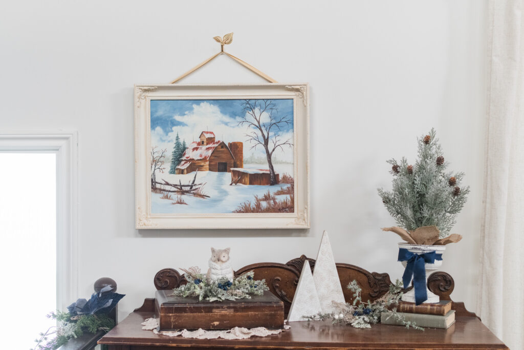 Vintage buffet with winter barn painting and elegant Christmas vignette