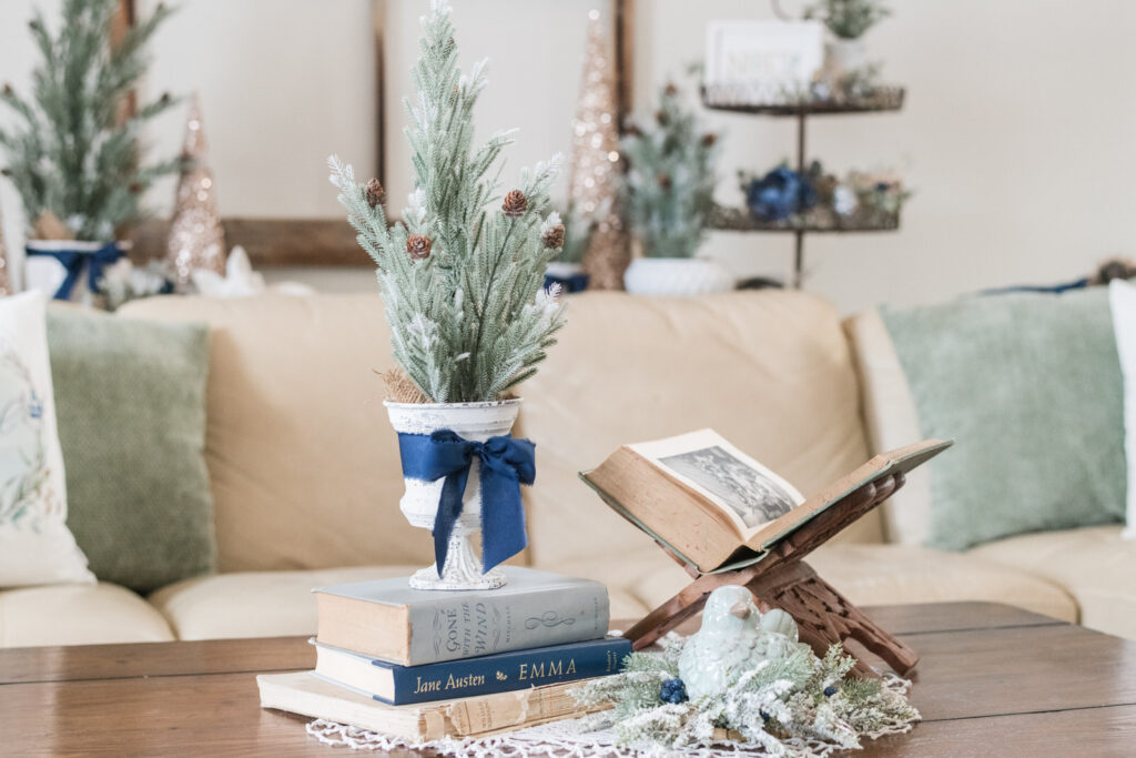 Coffee table with mini Christmas tree, open book, and winter greenery