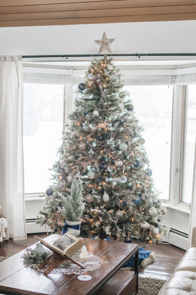 Christmas tree with navy ribbons and gold ornaments in cozy farmhouse living room