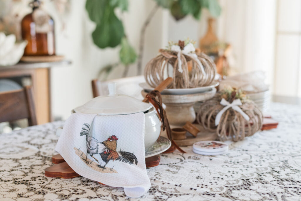 Fall dining room centerpiece with DIY jute pumpkins, turkey plates, soup tureen draped with tea towel, and velvet ribbon detail.