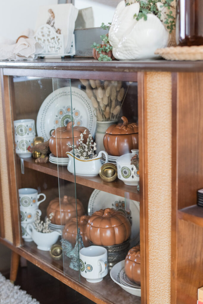 Vintage china cabinet filled with warm toned China and pumpkin dishes 