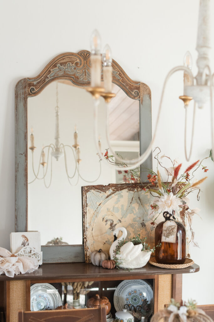 A peek inside my fall dining room from the kitchen, showing a Thrifted mirror, reflecting my chandelier, gathered with fall decor 