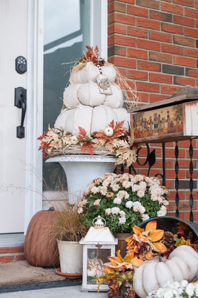 Close-up of white pumpkin topiary sitting in a painted cast-iron urn, accented with oak leaves, acorns, and a DIY resin tag and a handpainted mailbox