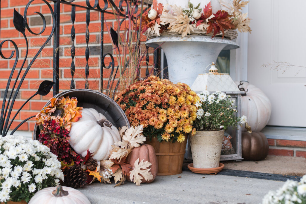 Cozy fall entryway decorated with terracotta pots, mums, pumpkins, and tipped apple barrels filled with fall florals.