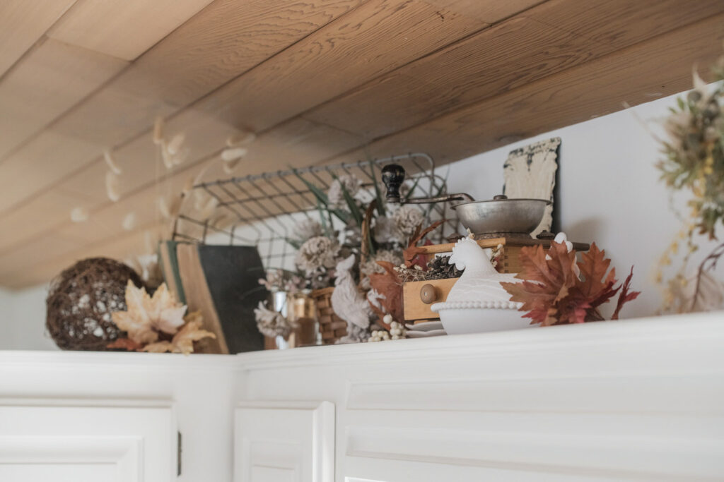 Wired basket tipped on its side, filled with vintage book, surrounded by fall decor, and a vintage coffee grinder 