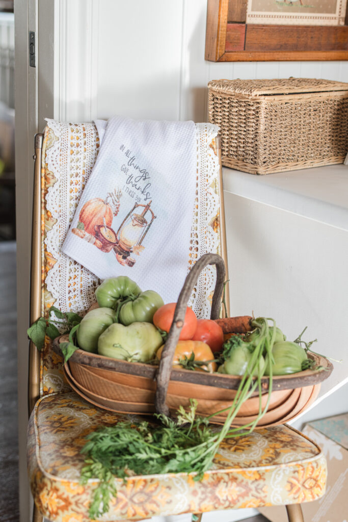 Thrifted vintage chair layered with a lace table runner and one of my tea towels with basket a freshly picked tomatoes and carrots 