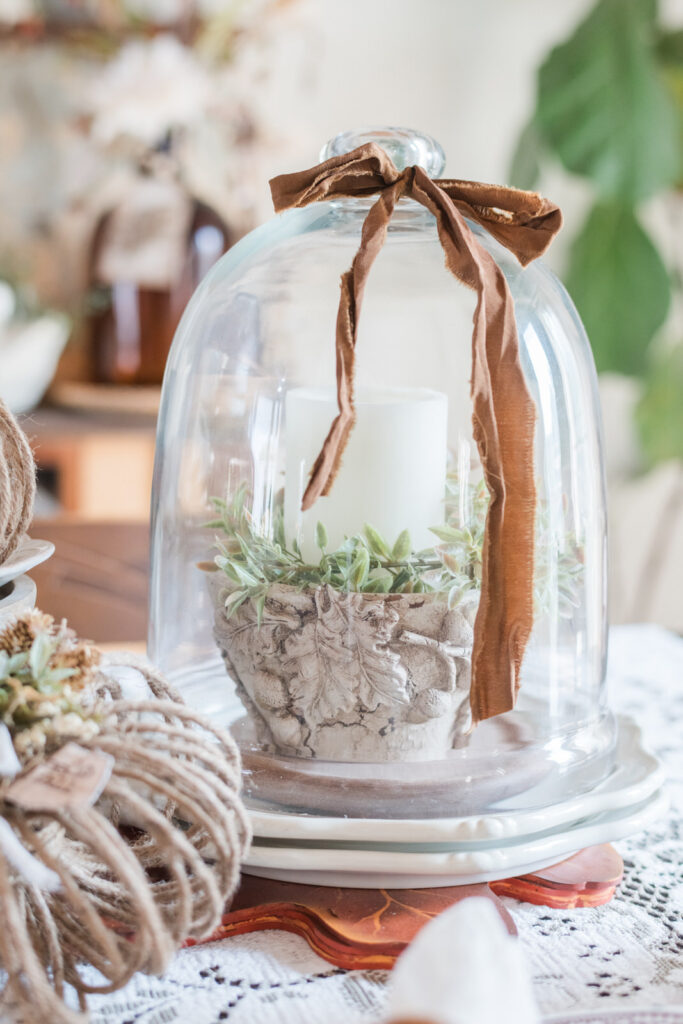 Fall vignette featuring a milk-painted wood bowl, greenery, and a candle under a glass cloche.