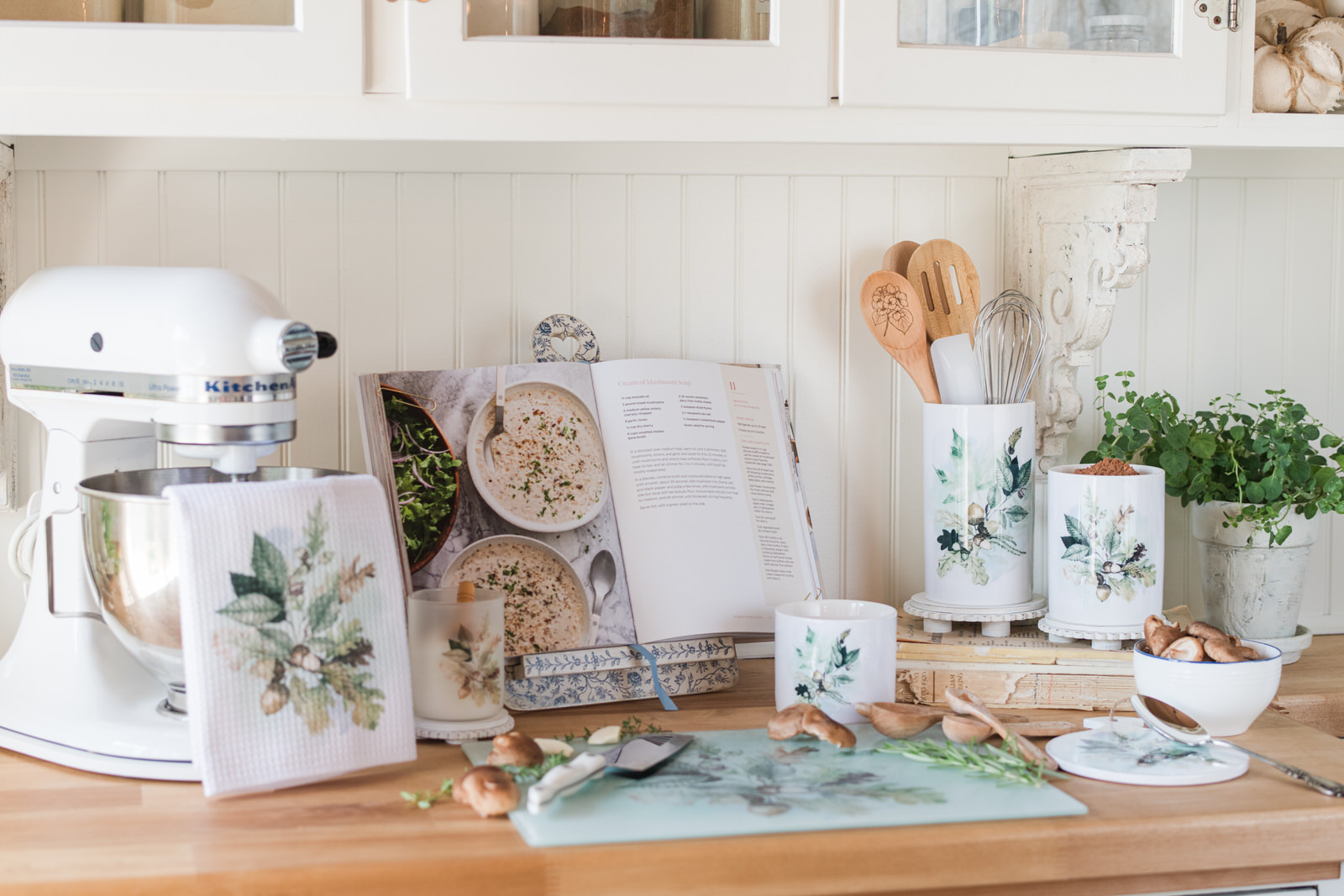 Woodland Collection glass cutting board beside a mixer, styled as a prep surface in a cozy fall baking corner.