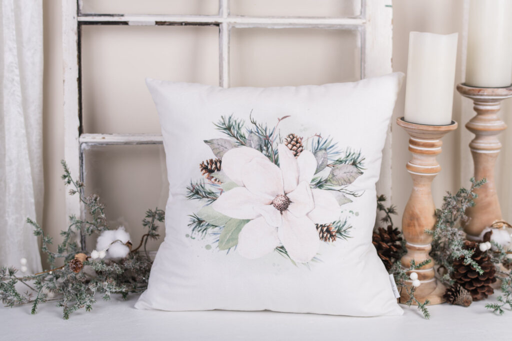 Magnolia Christmas pillows with magnolia blooms and pinecones on white velvet