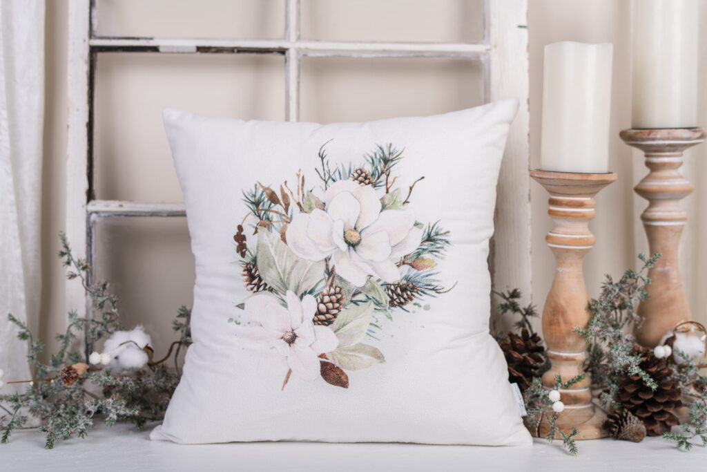 Magnolia Christmas pillows with watercolour magnolia blooms and pinecones on neutral background.