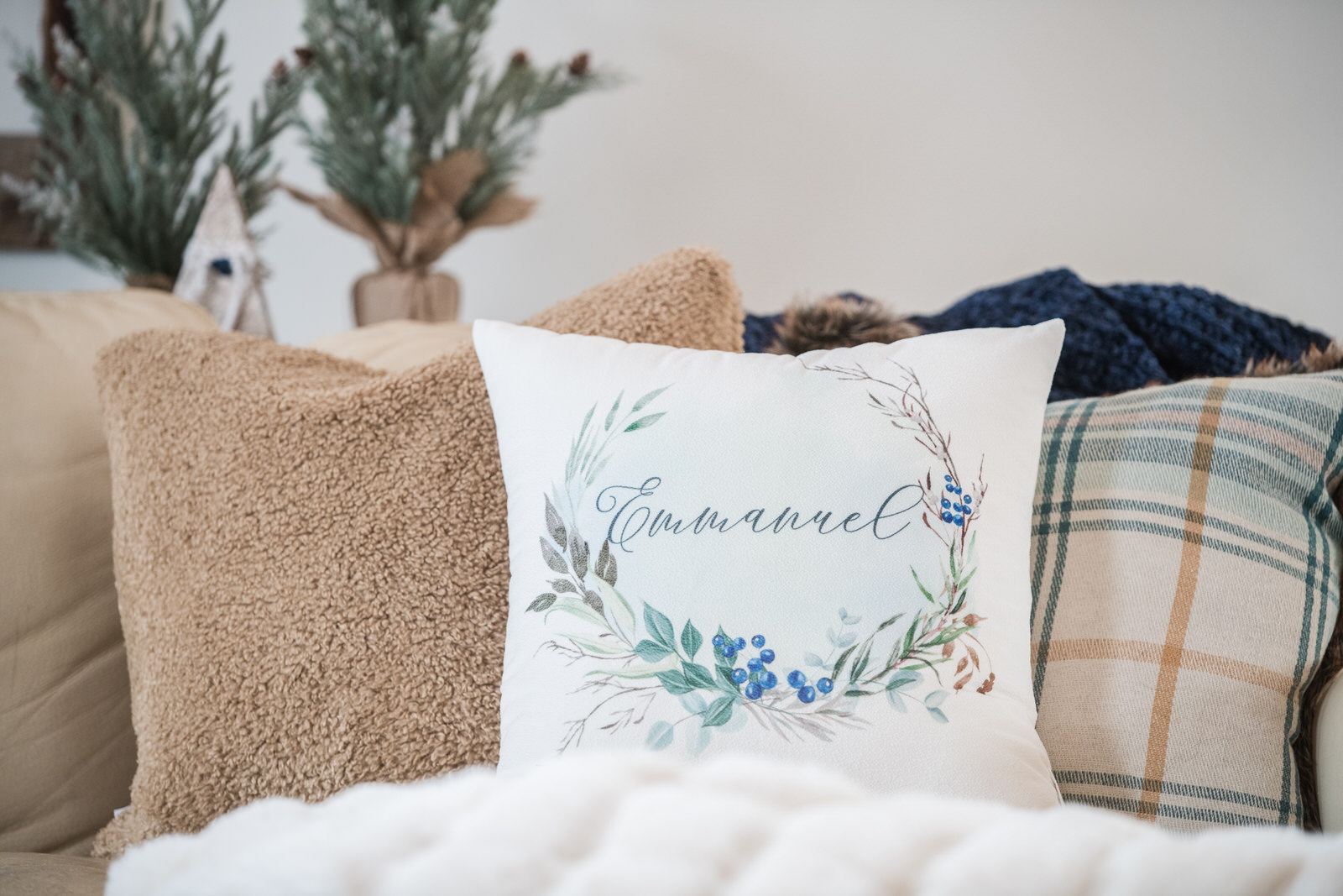 Emmanuel white velveteen pillow with blue berries, paired with textured and plaid pillows behind it