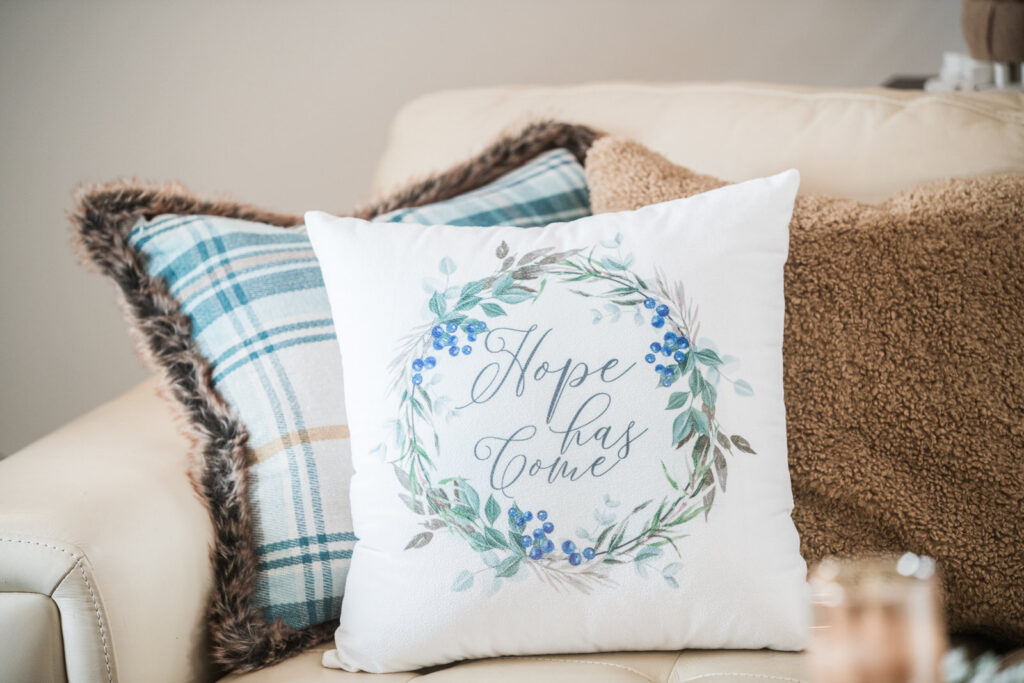 Pope has come velvet Christmas pillow paired with a faux fur and plaid pillow, and a caramel colored, textured pillow