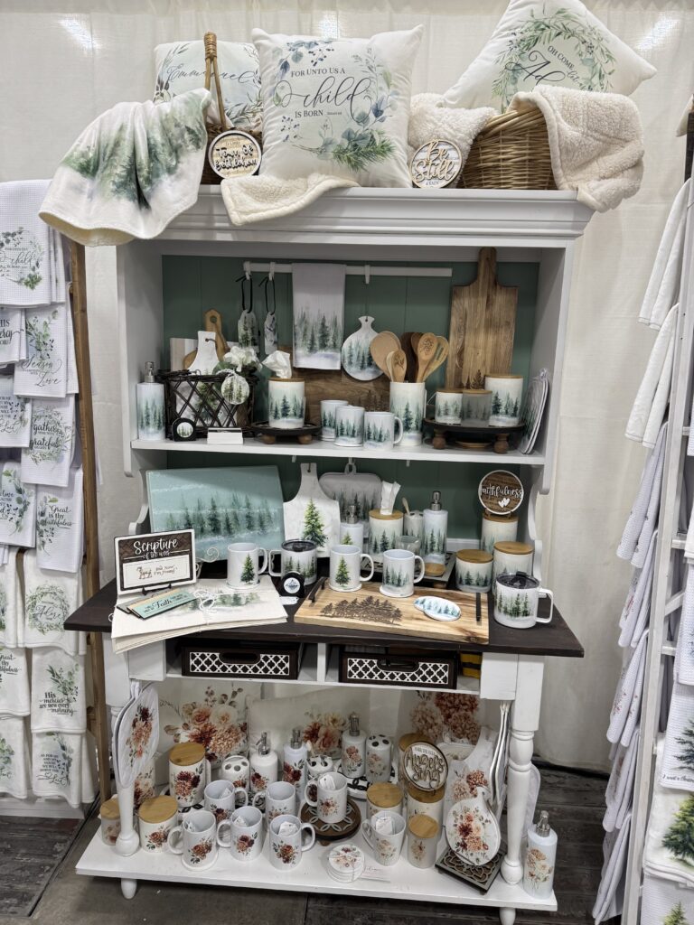 Christmas market booth display with handmade tea towels, mugs, and cozy home decor by At Home With Chic & Grace.