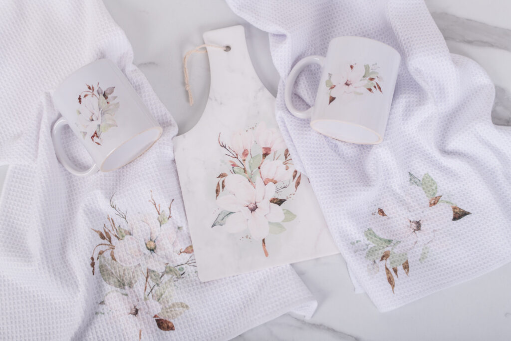Magnolia kitchen set with a rectangle, trivet, two tea towels, and two coffee mugs