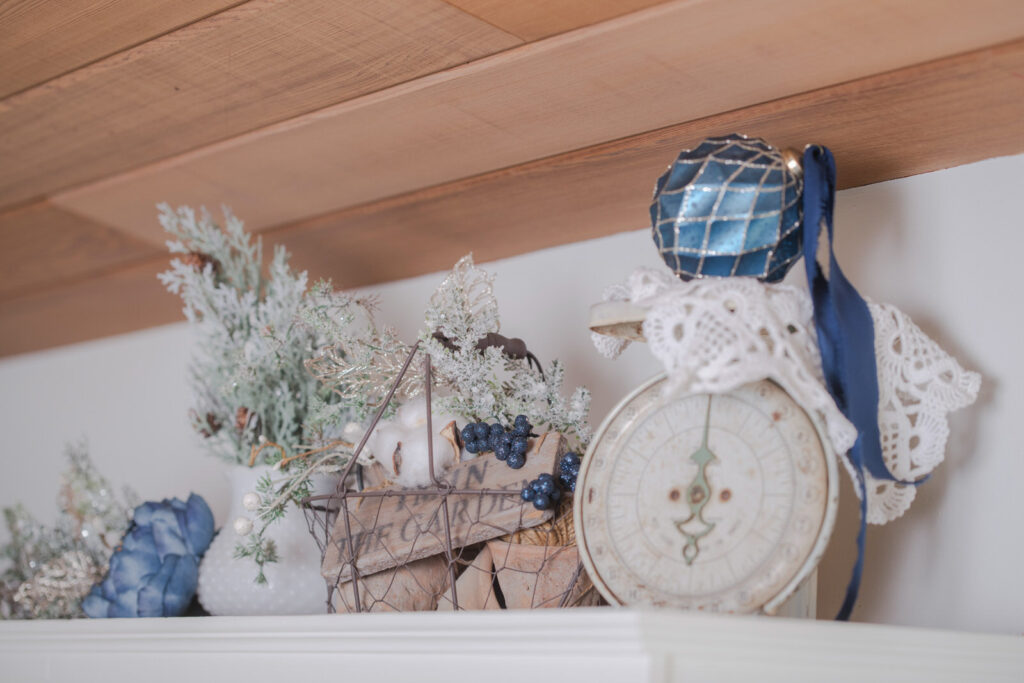 Winter kitchen decor displayed above cabinets using greenery, a vintage scale and soft blue details