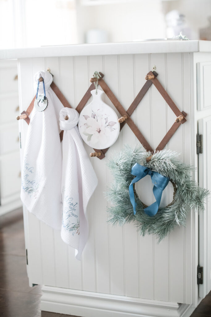 Painted kitchen island with accordion rack holding tea towels and holiday decor