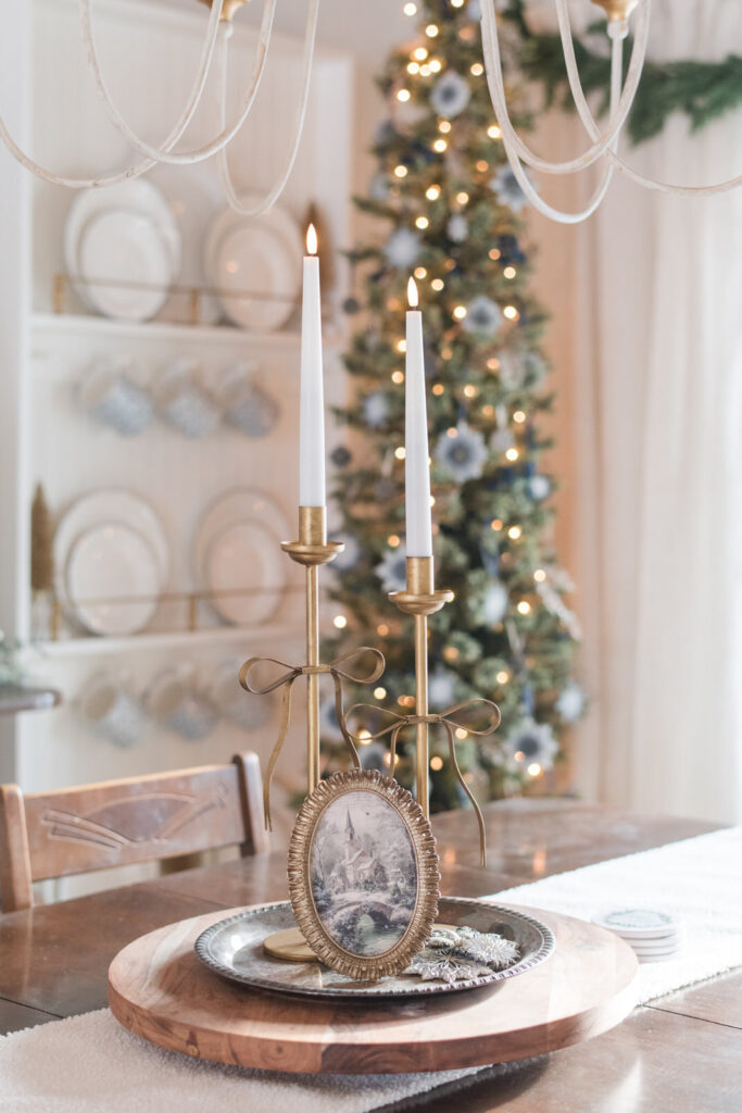Lazy Susan doubles as a charcuterie board, but it is styled with silver tray of vintage print in a gold frame, and DIY, gold candle sticks with battery operated candles in the dining room decorated for Christmas