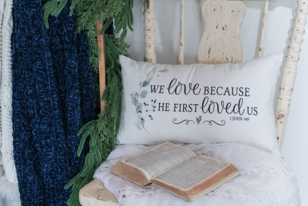 A pillow on a wooden chair with a crocheted blanket and an open Bible for Christmas