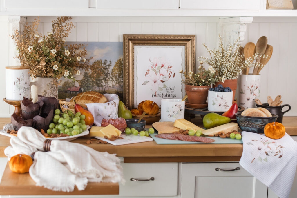 Magnolia brunch buffet with jam and berries in small canisters, a tea towel-lined bread basket, and a glass cutting board serving cheese and meats
