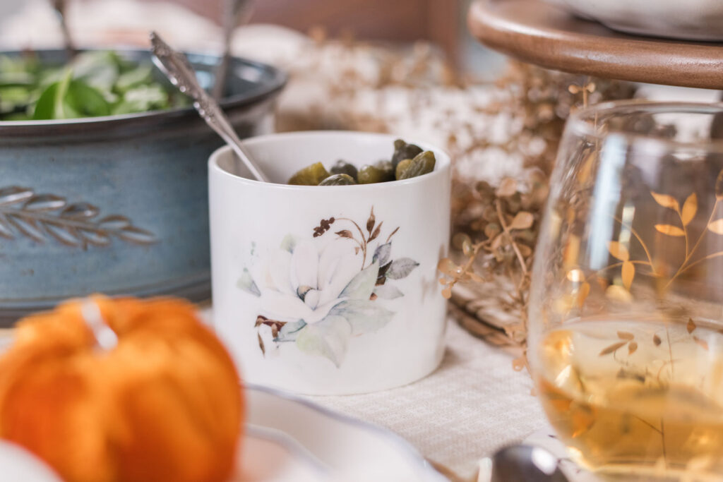 Small Magnolia canister filled with pickles and olives on a styled fall table