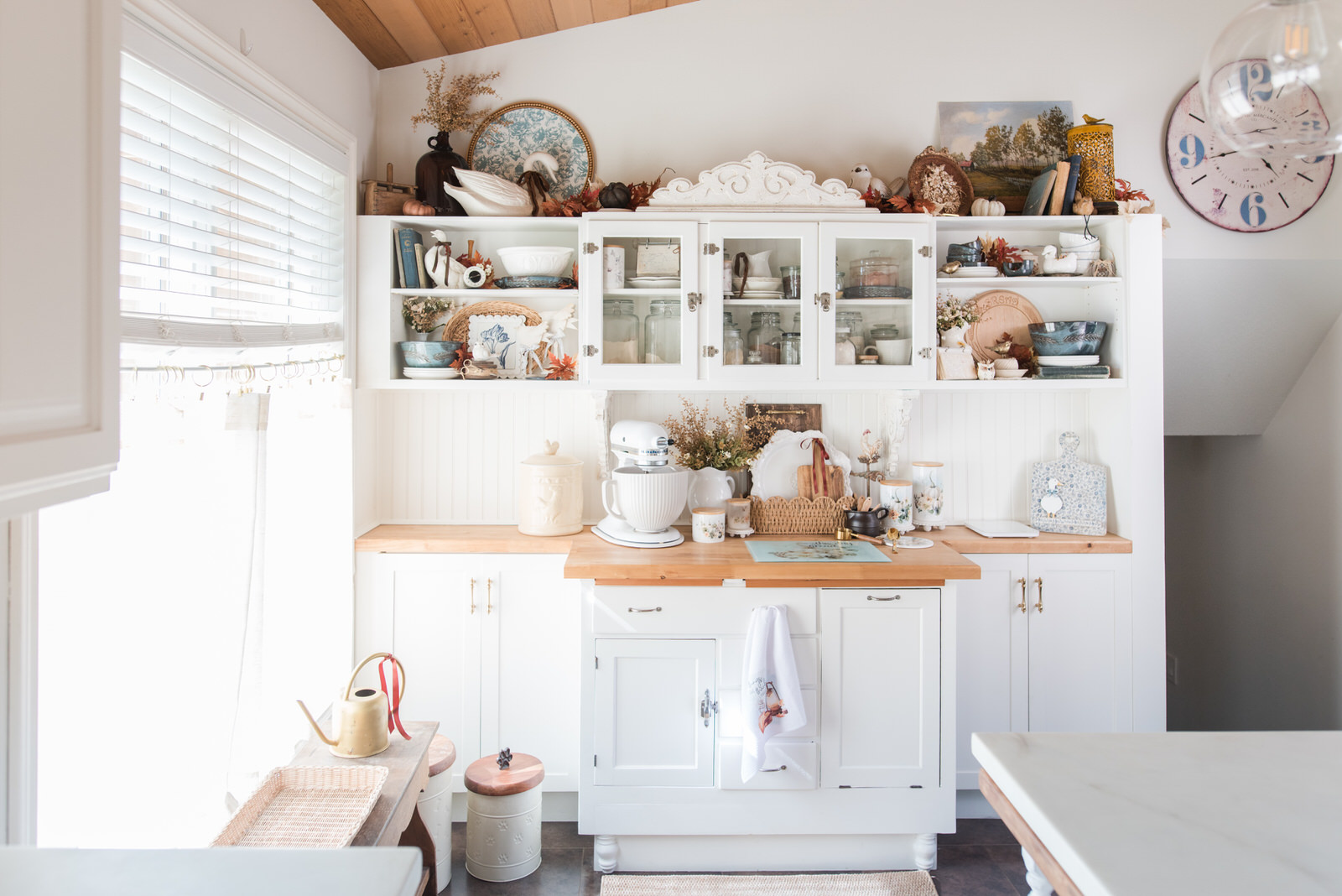Autumn home tour featured image: a cottage-inspired white kitchen with a KitchenAid mixer, Vintage Autumn canisters, and a basket of cutting boards on a butcher block counter
