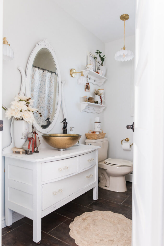 Guest bathroom styled with simple autumn bathroom decor, Magnolia pieces, pumpkins, and warm ribbon